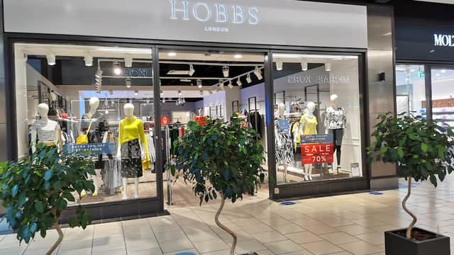Hobbs store entrance with mannequins in stylish clothing and a 70% off sale sign, flanked by small potted trees.