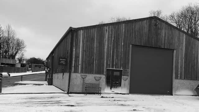 Wooden-clad workshop with a large garage door, snowy ground, and a bench outside in East Ayton, Yorkshire.