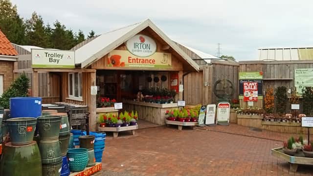 Entrance to Irton Garden Centre with colorful plants, pots, and signage, set in a charming outdoor space.