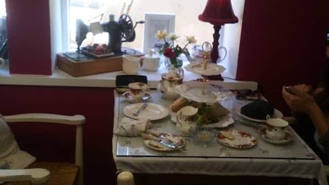 A cozy homeware shop with vintage tableware, a sewing machine, and floral decor, featuring a window with soft light.