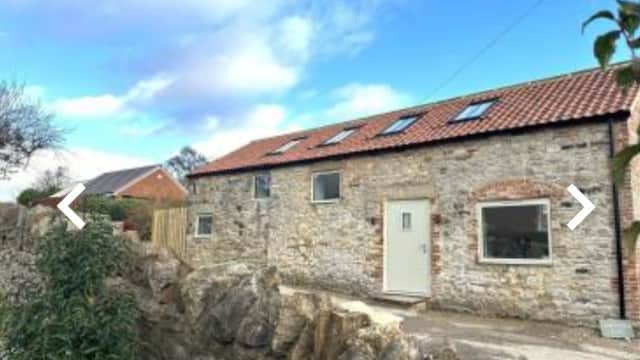 Stone building with a red-tiled roof, windows, and a door, set against a blue sky in North Cowton, Yorkshire.