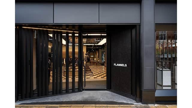 Modern storefront of Flannels with black facade, large glass doors, and a stylish interior visible through the entrance.