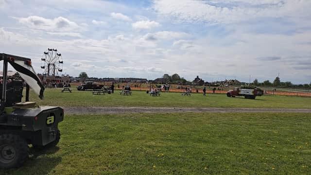 Farmer Copley's Parking lot with picnic tables, a ferris wheel, and an orange field under a cloudy sky in Featherstone.