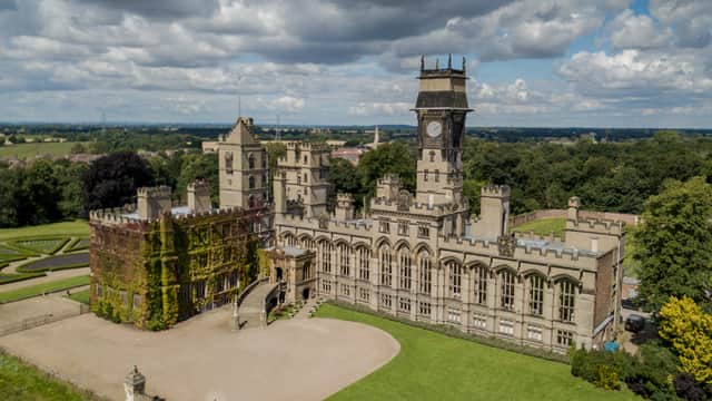 Historic Carlton Towers Estate features a grand castle with a clock tower, surrounded by lush greenery and gardens.