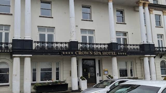 Elegant building with columns, "CROWN SPA HOTEL" sign, and parked white car in front, set in Spa Bridge, Yorkshire.