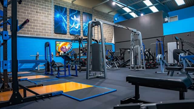 Modern gym interior with various workout equipment, blue and gray walls, and vibrant artwork.