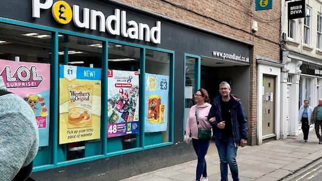 Poundland storefront with colorful signage; two people walking by on a city street in York, Yorkshire.