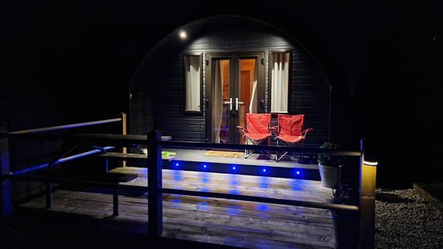 Cozy entrance of The Bryherstones Country Inn with two red chairs and blue lights illuminating the wooden deck at night.