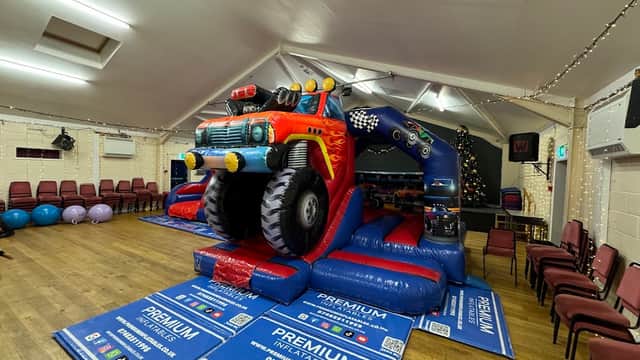 Brightly colored inflatable truck bouncer in a community hall with chairs and festive decorations.