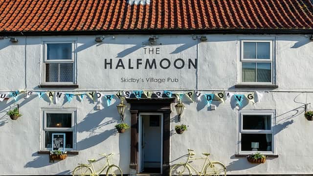 Charming white pub with a red-tiled roof, yellow bicycles, and decorative bunting in Skidby, Yorkshire.
