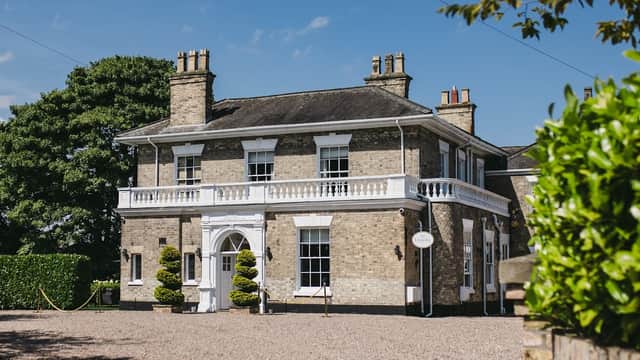 Elegant brick hotel with white trim, manicured hedges, and a sunny blue sky in Patrington, Yorkshire.