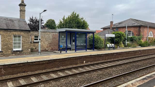 Train station platform with a blue shelter, benches, and brick buildings in Hutton Cranswick, Yorkshire.