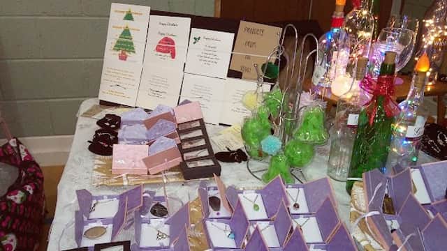 Jewelry displayed on tables with decorative items, menus, and festive decorations in a community hall setting.