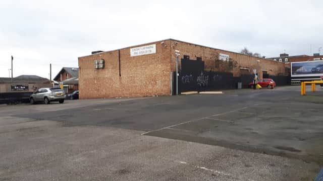 Brick wall of George Street Car Park with parked cars and graffiti, set in an urban environment in Wakefield, Yorkshire.