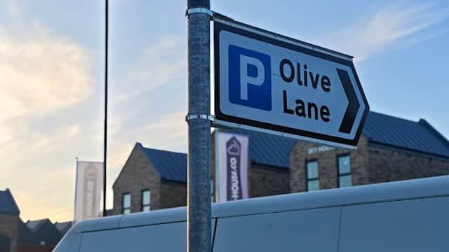 Sign for Olive Lane Car Park with a blue 'P' symbol, set against a clear sky and buildings in Darnall, Yorkshire.