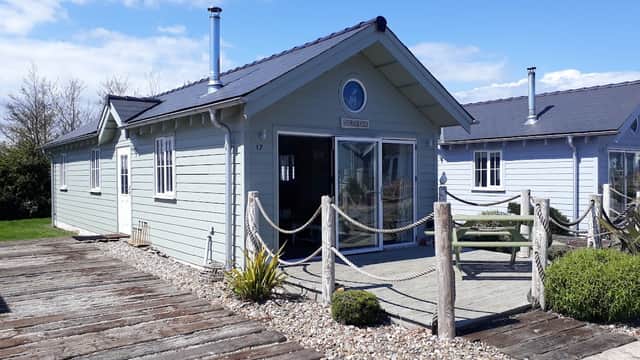 Salty Dog Beach House features a light blue exterior, wooden decking, and a scenic view under a clear sky.