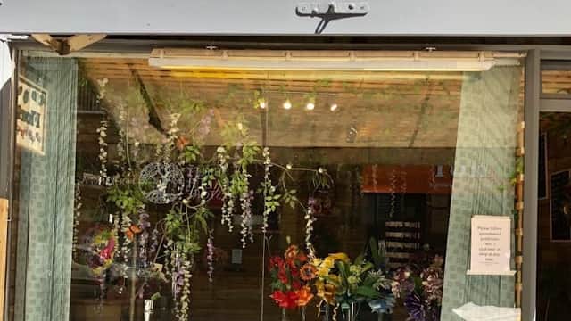 Floral shop window display featuring vibrant flowers, hanging greenery, and a welcoming sign in Bradford, Yorkshire.