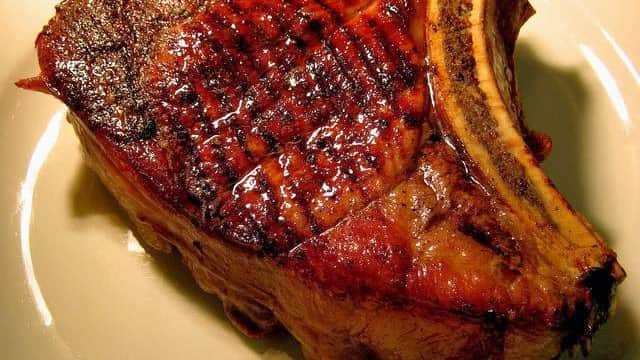 Juicy, grilled steak with a charred exterior, served on a white plate.