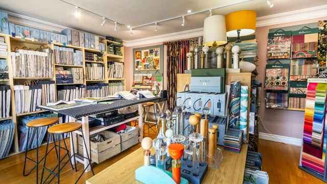Colorful homeware displays with fabric samples, shelves filled with materials, and stylish decor elements in a cozy shop.
