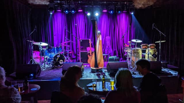 Stage set for a performance at Trades Club, featuring instruments like drums, a harp, and vibrant purple lighting.