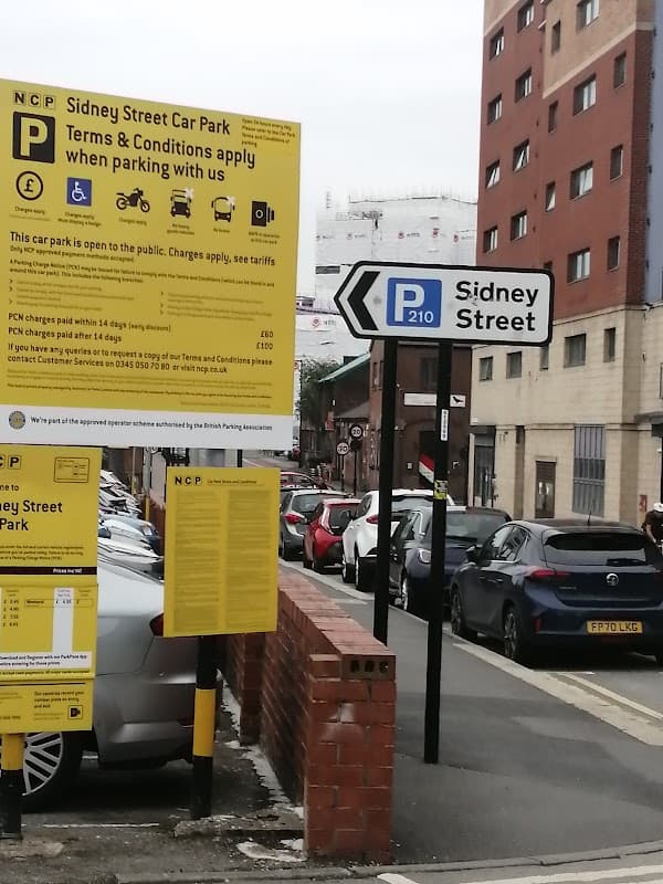 NCP Sidney Street car park sign with parking terms, street signs, and buildings in Sheffield, Yorkshire.