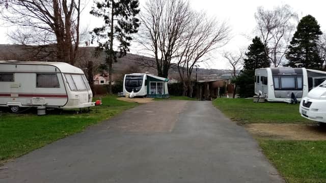 Caravan park with parked caravans, a pathway, and trees in a rural setting at Elland Hall Farm, Exley, Yorkshire.
