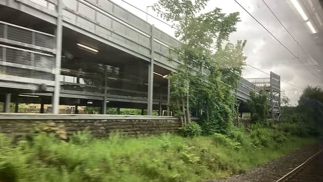 Multi-level car park surrounded by greenery and railway tracks under a cloudy sky in Sutton-in-Craven, Yorkshire.