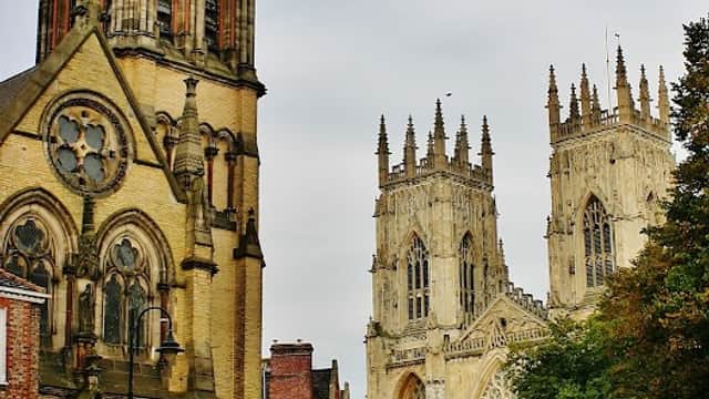 York Oratory stands alongside York Minster, featuring intricate architecture and a cloudy sky above.