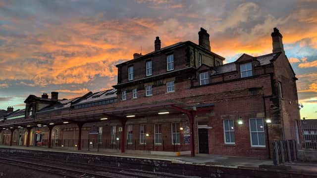 Sunset casts vibrant colors over Wakefield Kirkgate station, highlighting red-brick architecture and railway tracks.