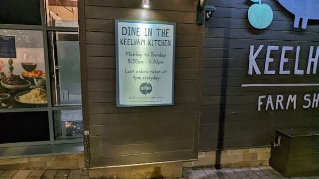 Sign for Keelham Kitchen, detailing hours and last order time, with festive lights on the exterior wall of the cafe.