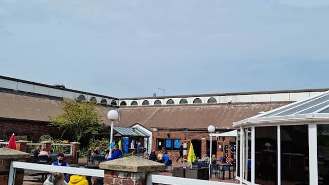 Outdoor seating area at Haven Far Grange Caravan Sales, with people enjoying the sunny day and colorful umbrellas.