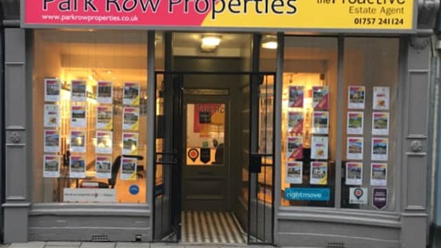 Shopfront of Park Row Properties with bright signage, window displays featuring property listings, and tiled entrance.