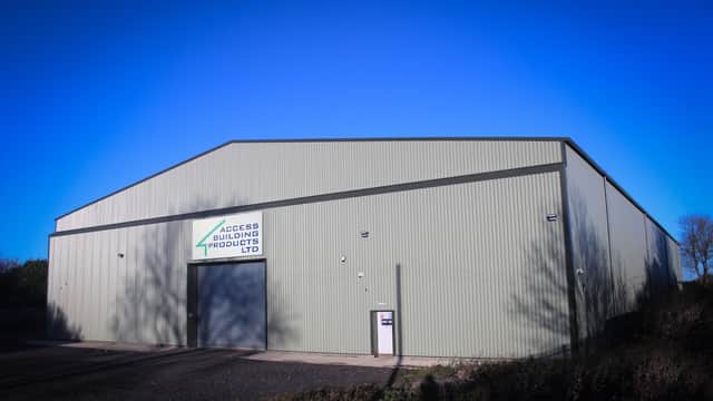 Large green industrial building with a sign for Access Building Products Ltd against a clear blue sky.