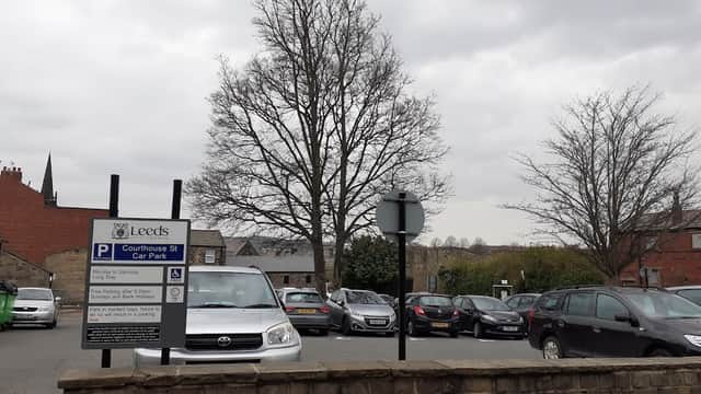 Courthouse Street Car Park with parked cars, a large tree, and a sign indicating parking rules under a cloudy sky.