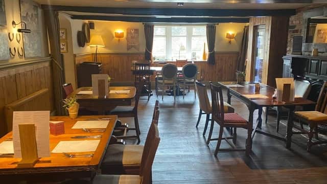 Cozy bar interior with wooden tables, chairs, and warm lighting, featuring a rustic ambiance and wall art.