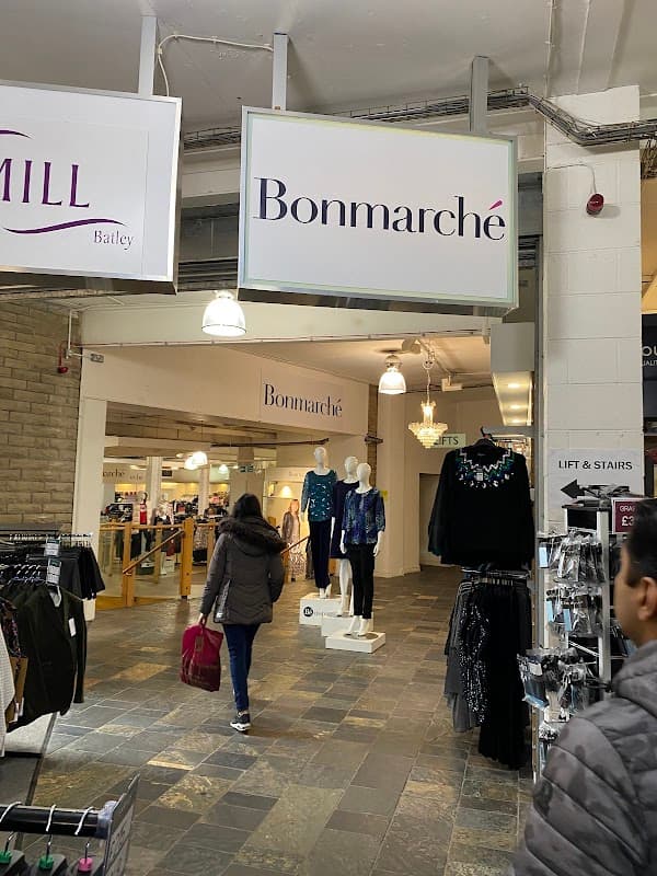 Entrance to Bonmarché with clothing displays and shoppers in a well-lit retail space at Batley Mill.