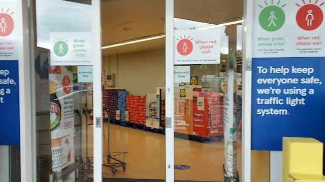 Entrance to Tesco Superstore with traffic light system signs and green/red indicators for safety.
