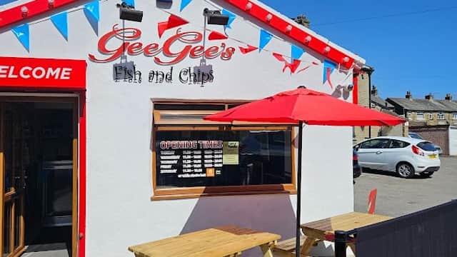 Exterior of Gee Gee's Fish and Chips, featuring a red and white building, outdoor seating, and colorful bunting.