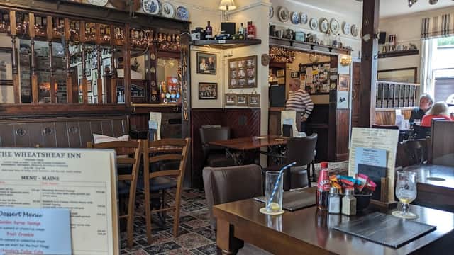 Cozy bar interior with wooden furniture, decorative plates, and patrons enjoying meals in a warm atmosphere.