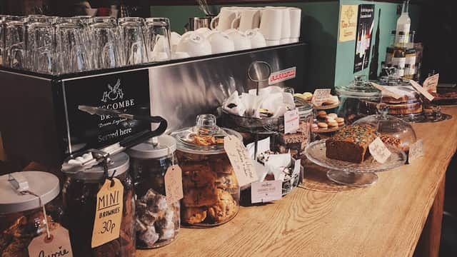 Glass jars filled with baked goods, a wooden counter, and a coffee machine in a cozy cafe setting.