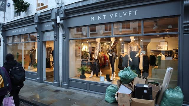 Mint Velvet shop front in York, featuring stylish clothing displays and green bags piled outside.
