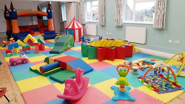 Brightly colored play area with a bouncy castle, soft toys, and various childrenβs play equipment on foam tiles.