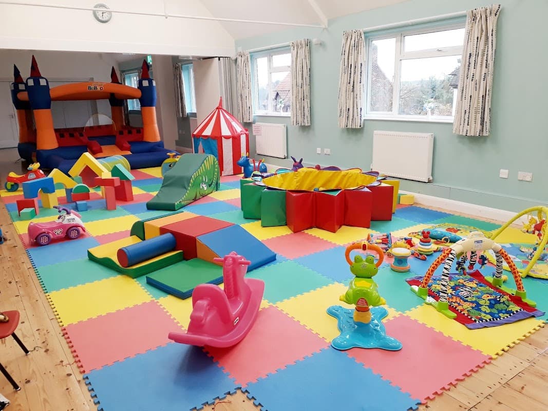 Brightly colored play area with a bouncy castle, soft toys, and various children’s play equipment on foam tiles.