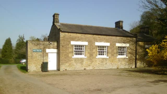 Stone building with white windows and door, surrounded by trees and gravel path in Bulmer, North Yorkshire.
