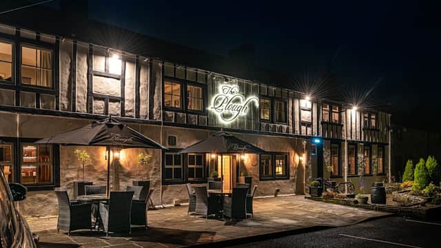 The Plough restaurant at night, featuring outdoor seating, a lit sign, and a traditional Yorkshire stone facade.