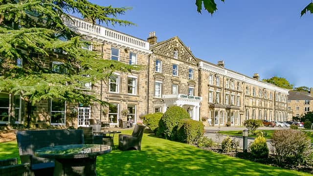 Cedar Court Hotel exterior with manicured lawns, seating area, and clear blue sky in Harrogate, Yorkshire.