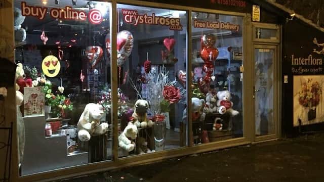 Bright storefront of Crystal Roses Florist featuring flowers, balloons, and plush toys, with a welcoming display.