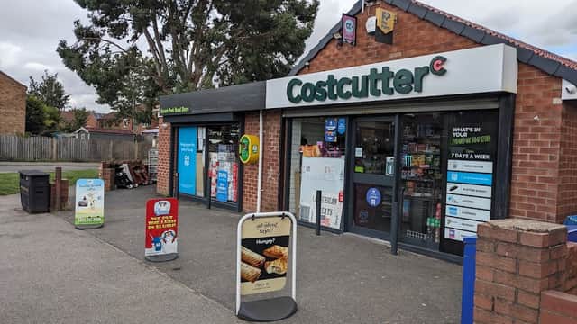 Costcutter storefront with large windows displaying products, signage, and promotional boards outside.