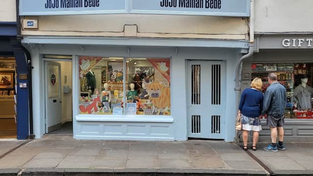 Colorful storefront with playful window display, featuring children's clothing and accessories, in a charming street setting.