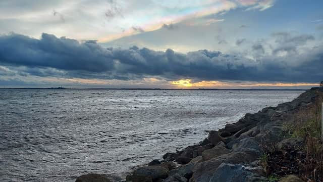 Carpark and viewing area by the river, with rocky shoreline and dramatic clouds at sunset in North Ferriby, Yorkshire.